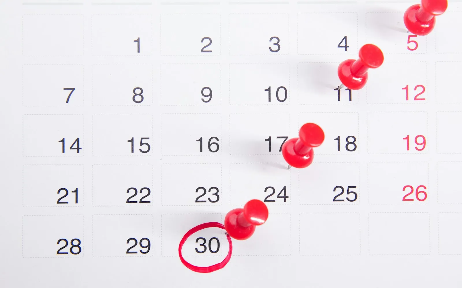 Calendário com alfinetes vermelhos marcando datas e o dia 30 circulado.