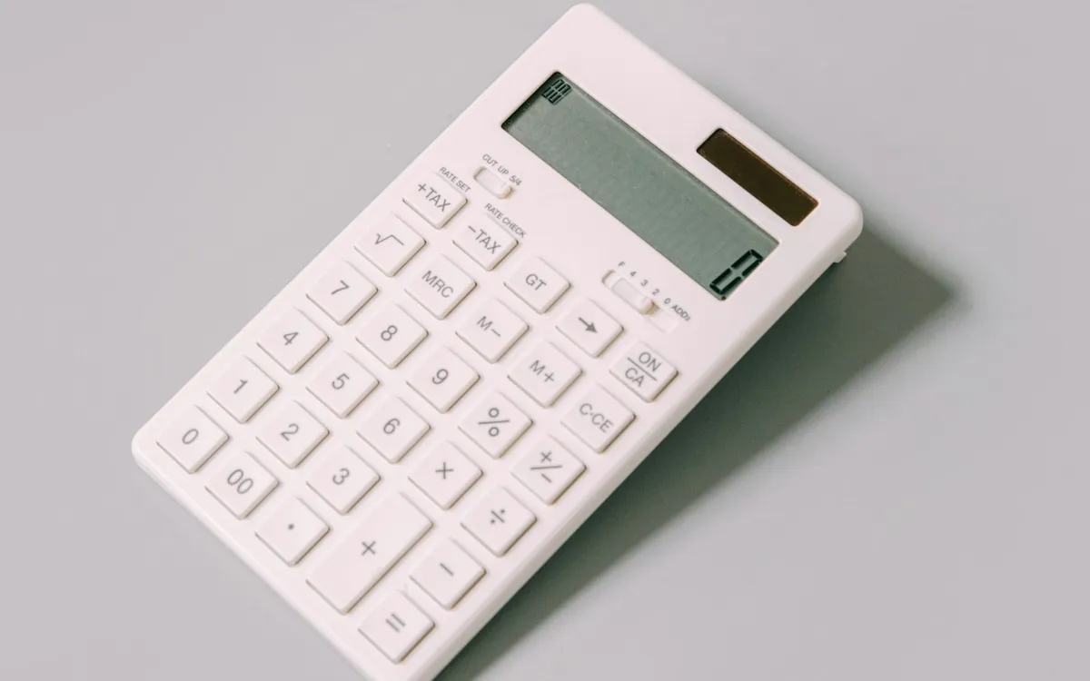 Calculadora branca sobre uma mesa clara.