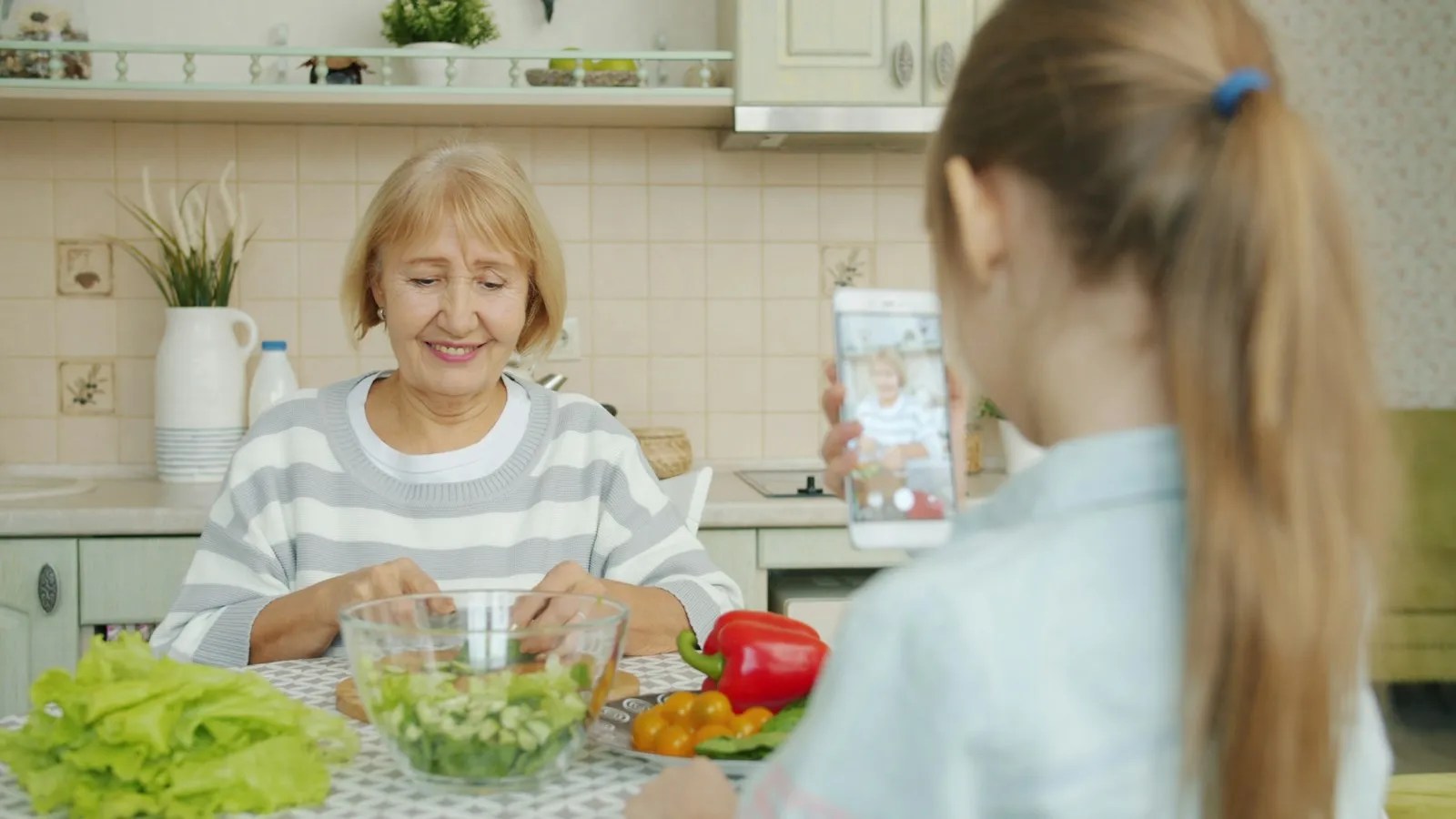 Avó e neta preparando uma salada juntas na cozinha de casa.